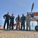 five people standing in front of an airplane
