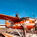 one person sitting on top of and a second person standing in front of an airplane