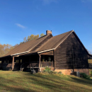 a brown, wooden building on a grassy hill