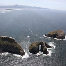 The Pacific Ocean crashes around the bases of three huge, arched, grassy islands