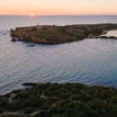 Aerial view of a beach with the sun setting in the background