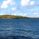 A small island in the distance surrounded by ocean water.