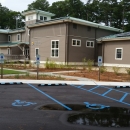 A brown-and-white building with a garden and several parking spaces