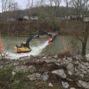 Crane removing dam with danger sign in the foreground