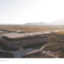 A modern building with various walkways and overlooks adjacent to an large open meadow.