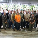 Awardees from the USFWS ceremony on Maui gather for a group photo in front of a plant wall of a dimly lit room.