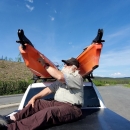 Watercraft inspector physically inspecting two kayaks on top of truck roof rack for aquatic invasive species.