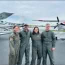 four people standing in front of airplans