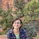 Woman smiles at camera with desert-type habitat in background 