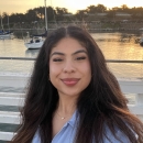 a woman smiling with a body of water behind her