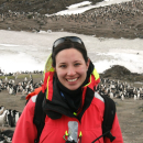  Person poses for a photo with water and penguins in the background