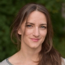 A white woman with brown hair smiles.