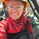 Alex smiling in a yellow construction hat, goggles, and a red bandana