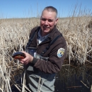 A man standing in a wetland holding a turtle