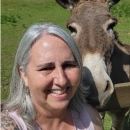 Beth smiles next to a donkey