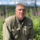 man with grey hair in field clothes