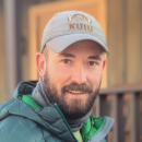 Man in green jacket smiles at the camera