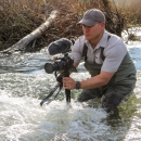 a man in a river holding a camera