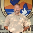 An image of a staff member standing in front of a refuge sign.