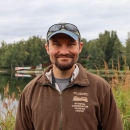 Man with beard and baseball hat wearing a brown National Conservation Training Center jacket