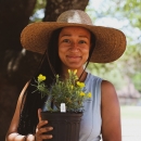 Picutre of Jade Florence under a tree holding a potted plant.