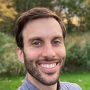 a headshot of a white man with brown hair and a short beard