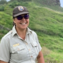 woman wearing USFWS uniform stands on a hillside. 