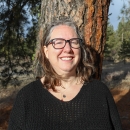 Portrait of a woman standing in front of a pine tree