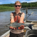 Woman on boat holding fish and smiling