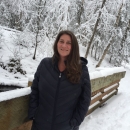 Libby stands on a bridge in the snowy forest. 