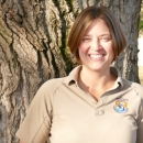 Woman stands in front of tree and smiles.