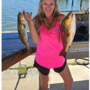 Michelle stands with two fish in a pink shirt and black short