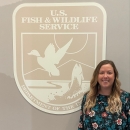 a woman stands and smiles next to a large Service logo