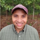 Rafael smiling in a green shirt and red baseball cap.