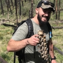 a man holding up an animal bone in the woods