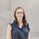 a headshot of a white woman with brown hair and glasses