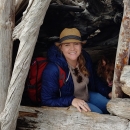 A woman with a red backpack and a tan hat on smiling