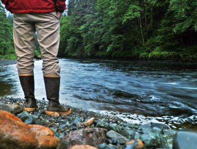 man standing by a river in rain gear