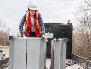 Person standing in the back of a flatbed truck examining artificial bat roosts