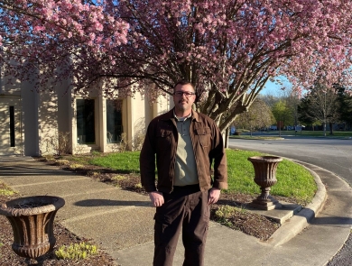 USFWS employee standing in front of blooming trees & building