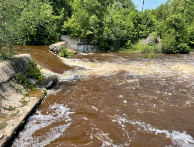 a breached dam with river water flowing through the gap