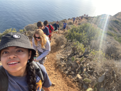 A woman taking a selfie with a line of hikers behind her