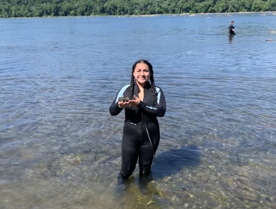 Intern in river holding a freshwater mussel