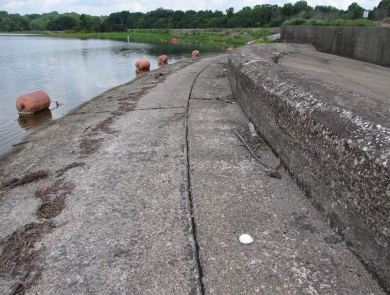 Curved cement infrastructure with green trees and a lake in distance