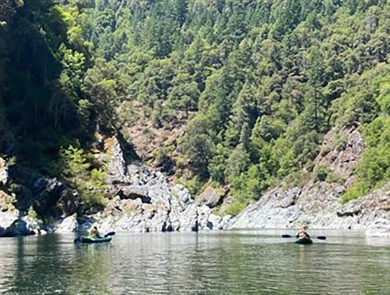 A group of people kayaking on a lake with mountains in the background