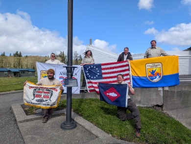 6 people on hill holding 4 flags, fish pennant
