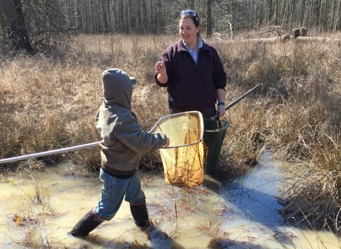 Young boy and FWS biologist catching frogs in net at Big Oaks NWR