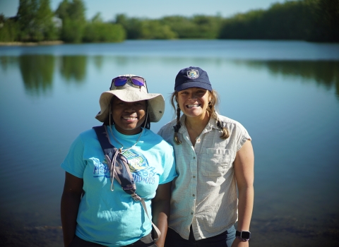 two women standing by a lake