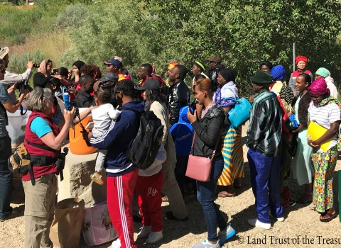 A group of refugees gather to bird watch at the Hyatt Hidden Lakes Reserve