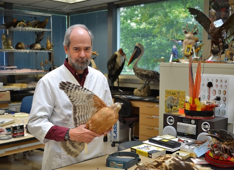 a man standing in a room holding a stuffed bird